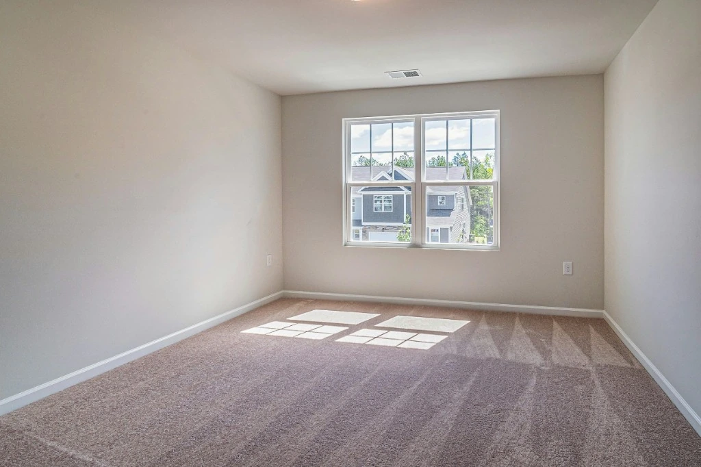 Beige wall-to-wall carpet in a bright empty room after cleaning