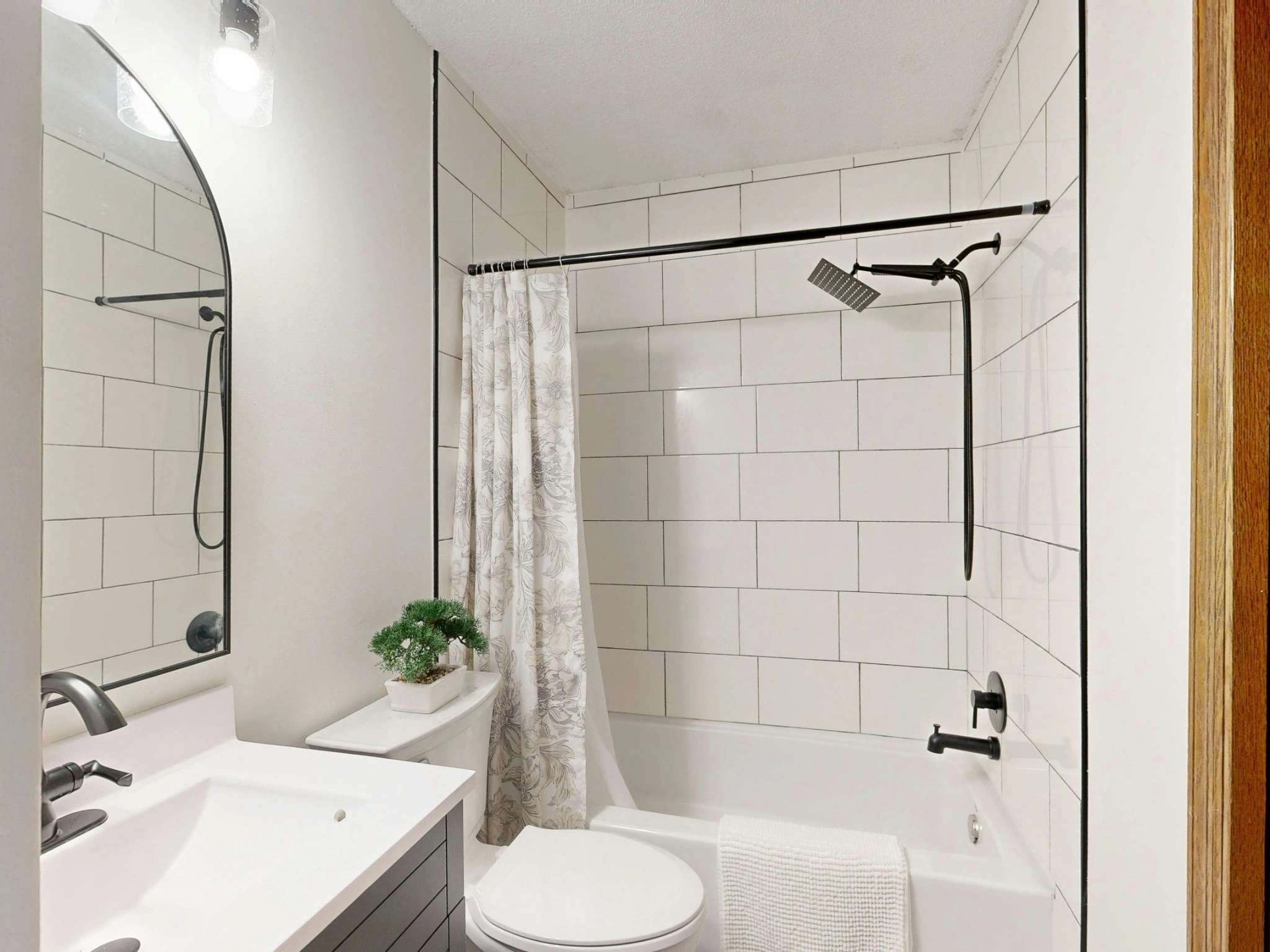 Spotless modern bathroom with white tile and matte black fixtures after professional cleaning