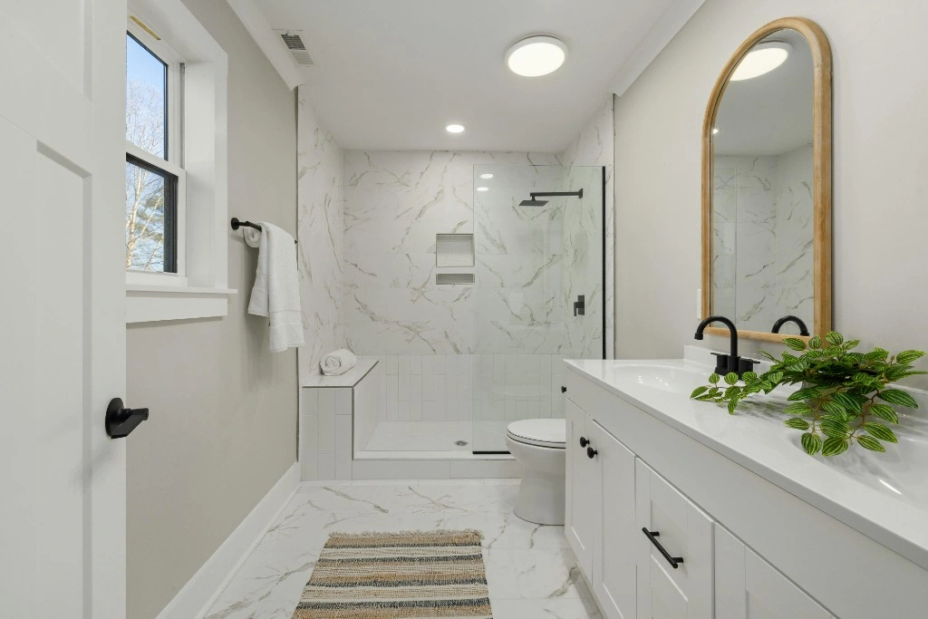 Bright bathroom with double vanity, walk-in shower, and gleaming surfaces