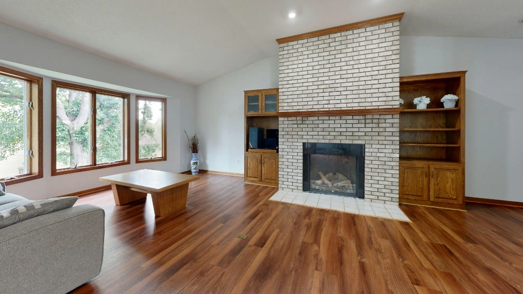 Clean living room with fireplace, wood floors, and clear windows